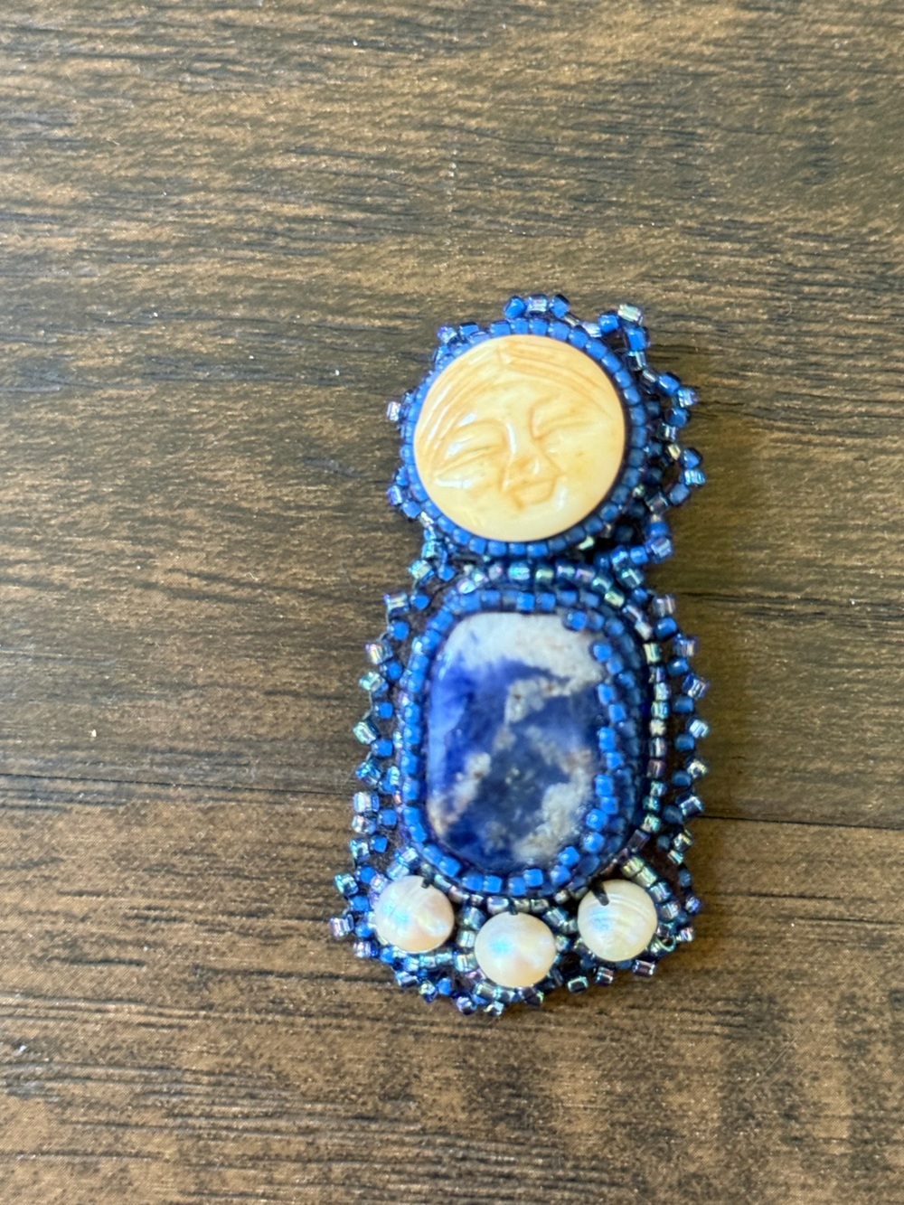 hand-beaded artisan brooch with moon face